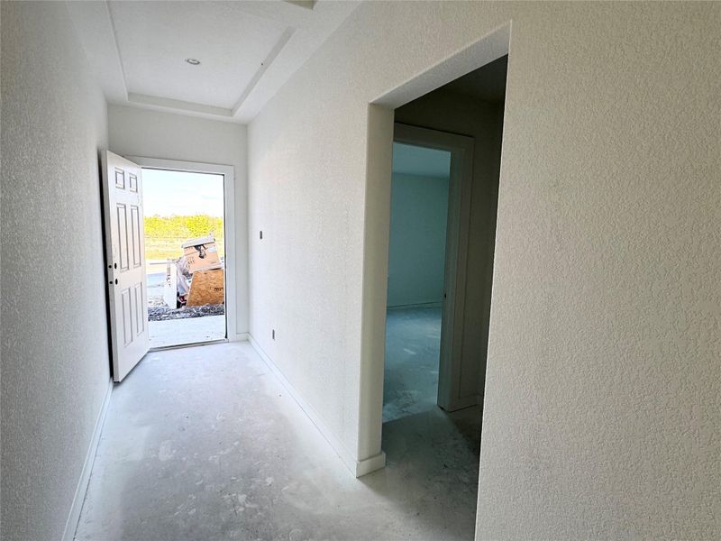 Hallway with a textured wall and concrete flooring Hallway with a textured wall and concrete flooring