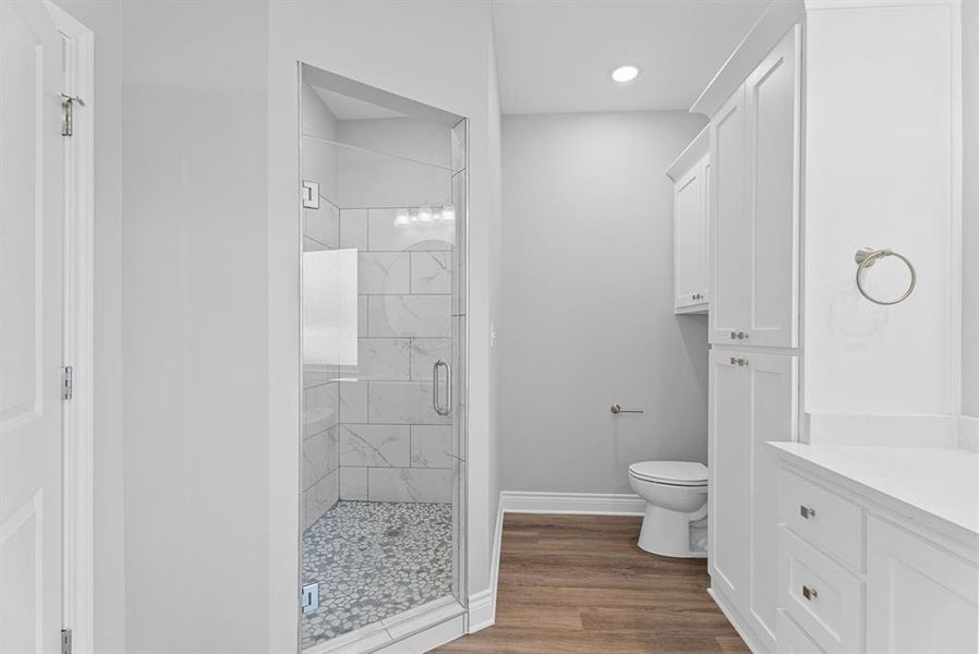 Full bathroom featuring a marble finish shower, dark wood-style flooring, vanity, and recessed lighting