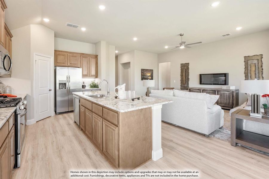 Open-concept kitchen and living area with granite island, wood cabinets, stainless appliances, and light hardwood floors