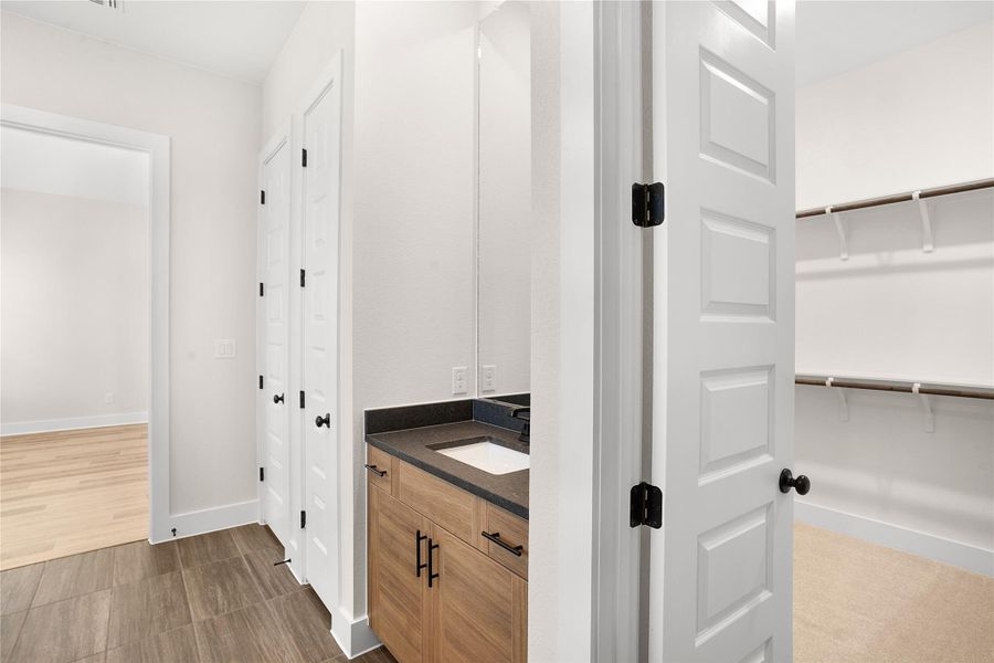 Well-appointed bath featuring a modern vanity with ample storage and stone counters, adjacent to a convenient walk-in closet. Well-appointed bath featuring a modern vanity with ample storage and stone counters, adjacent to a convenient walk-in closet.
