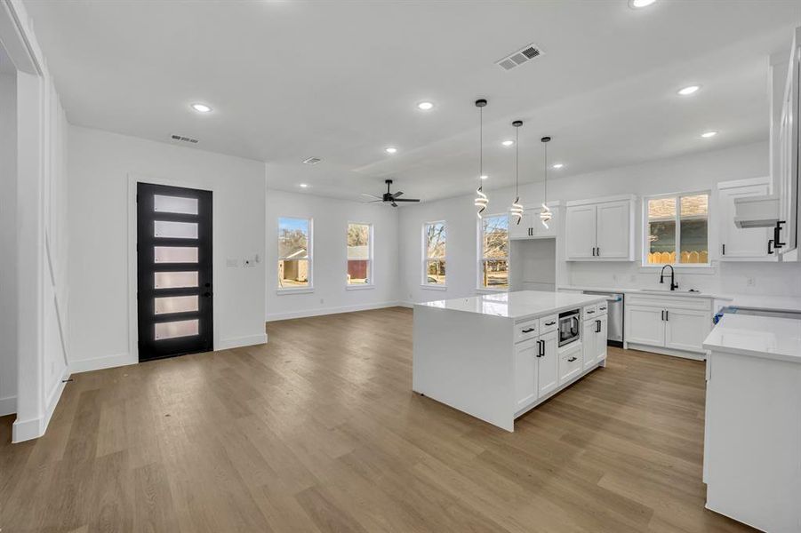 Kitchen with pendant lighting, a center island, sink, and white cabinets