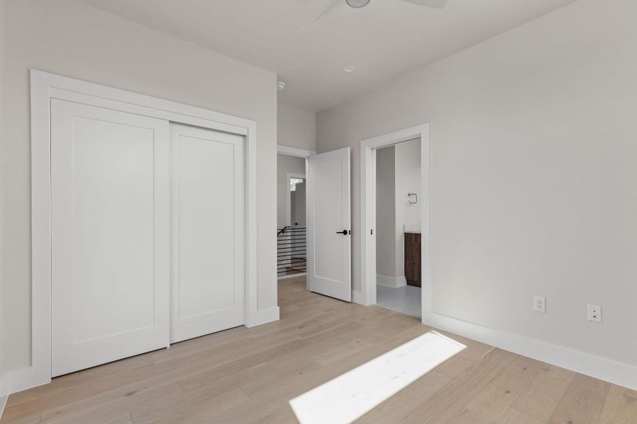 Unfurnished bedroom with light wood-style floors, a closet, ensuite bathroom, and baseboards