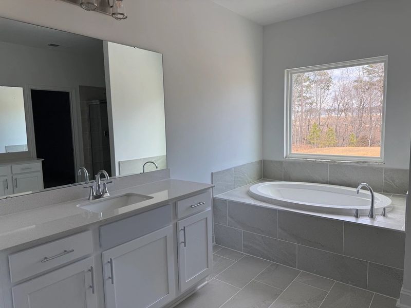 Primary Bath featuring the AW Collection® Coastal - Spa-like with white cabinets and light tile. Primary Bath featuring the AW Collection® Coastal - Spa-like with white cabinets and light tile.