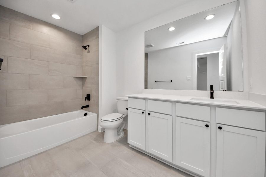 Secondary bath features tile flooring, bath/shower combo with tile surround, light stained wood cabinets, beautiful light countertop. Sample photo of completed home with similar floor plan. Actual colors and selections may vary. Secondary bath features tile flooring, bath/shower combo with tile surround, light stained wood cabinets, beautiful light countertop. Sample photo of completed home with similar floor plan. Actual colors and selections may vary.