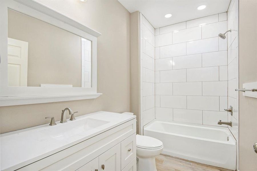 Full bath with vanity, wood finished floors,  shower combination, and recessed lighting