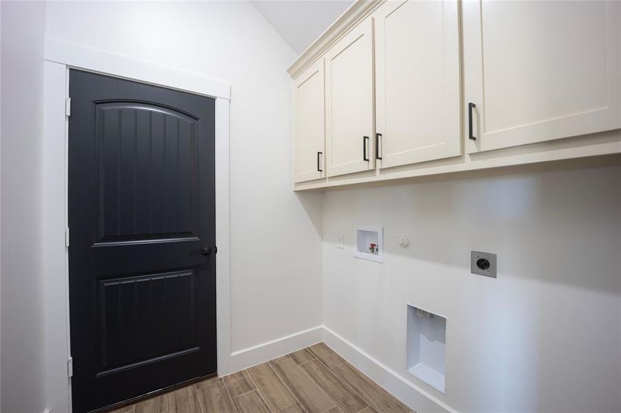 Laundry room featuring wood finish floors, gas dryer hookup, hookup for an electric dryer, hookup for a washing machine, and cabinet space