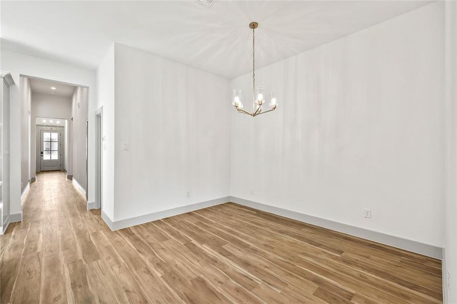 Empty room featuring light wood-style flooring, a chandelier, and recessed lighting