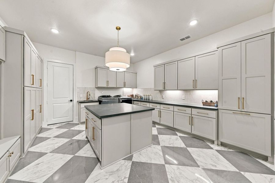 An exceptional oversized utility room thoughtfully designed with extensive custom cabinetry, abundant counter space, and impressive storage throughout.