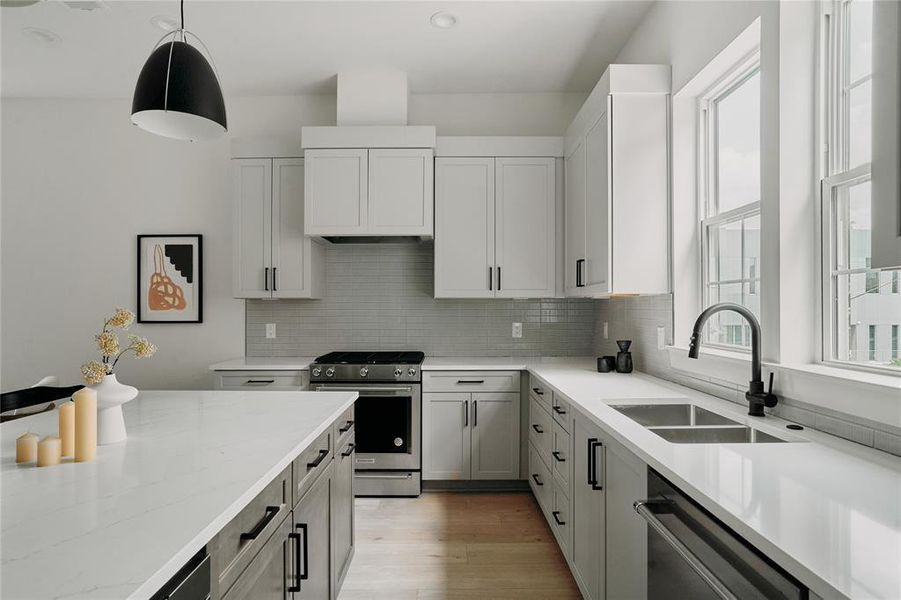 Modern kitchen featuring white shaker cabinetry, stainless steel appliances, light countertops, a tile backsplash, and a large central island