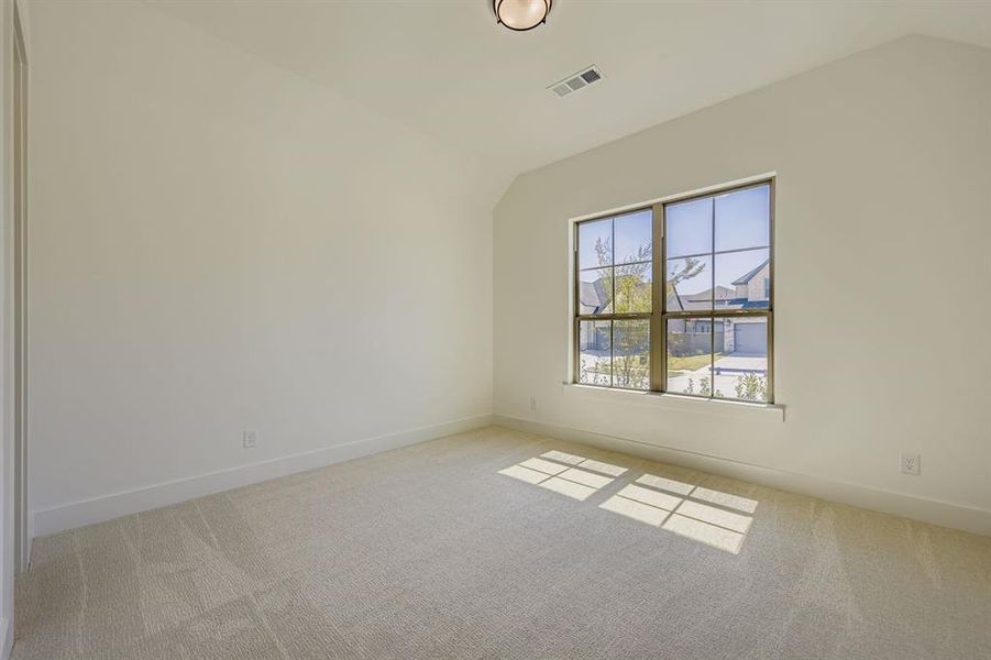 Spare room with vaulted ceiling and light carpet Spare room with vaulted ceiling and light carpet