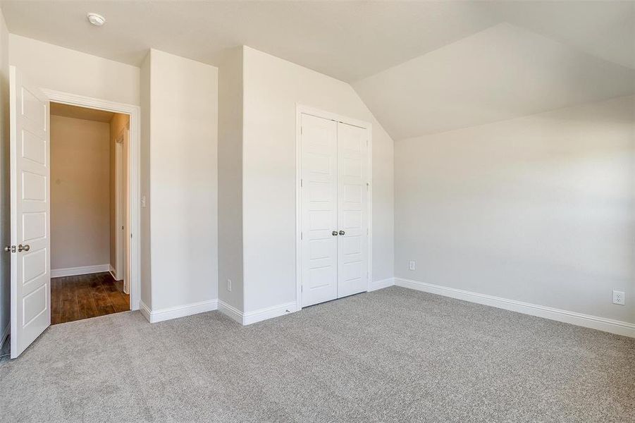 Unfurnished bedroom featuring light carpet, lofted ceiling, and a closet