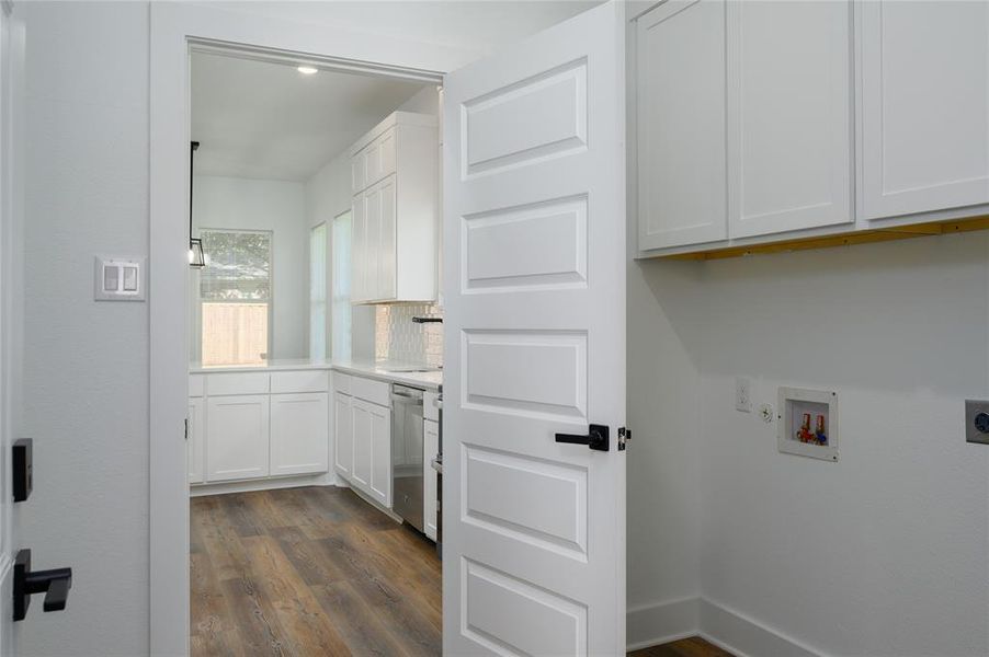 Clothes washing area with cabinets, electric dryer hookup, gas dryer hookup, hookup for a washing machine, and dark hardwood / wood-style flooring