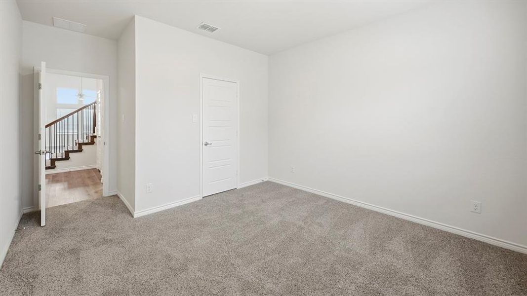 Carpeted room featuring a contemporary five-panel door with brushed nickel hardware, white baseboards, and a doorway opening to a staircase with dark wood-finish treads and white risers