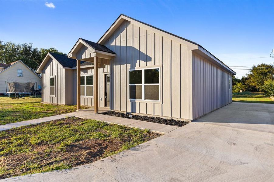 Modern farmhouse featuring board and batten siding, a trampoline, and a front yard Modern farmhouse featuring board and batten siding, a trampoline, and a front yard