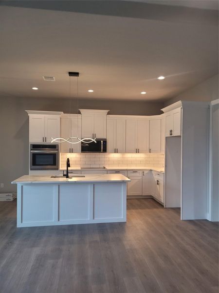 Kitchen with pendant lighting, white cabinets, oven, tasteful backsplash, and recessed lighting