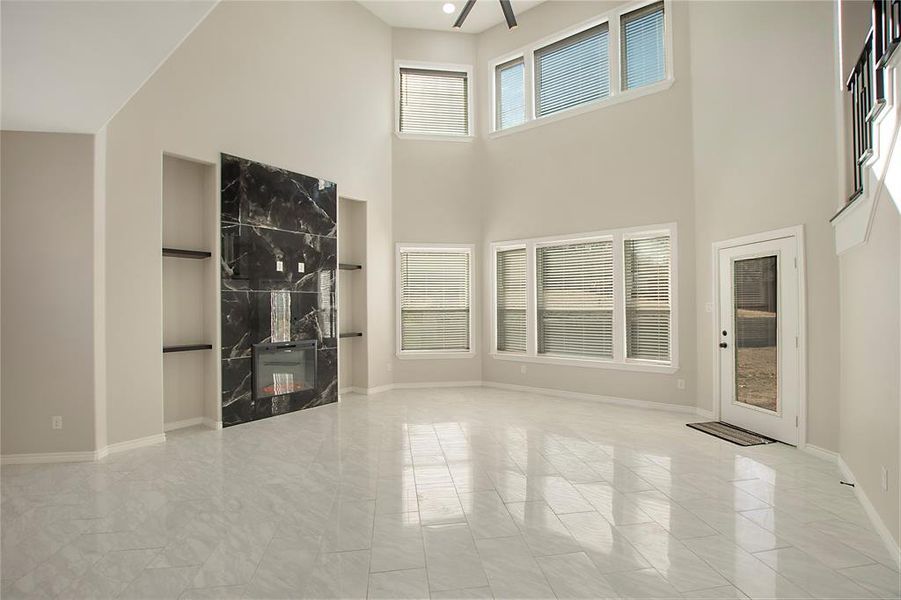 Unfurnished living room with a towering ceiling and a fireplace