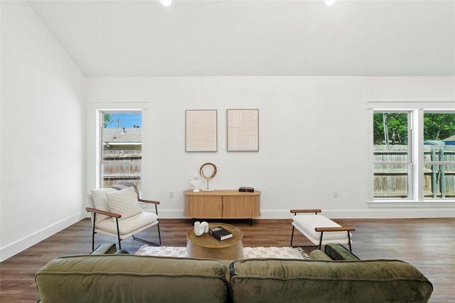 Living room with plenty of natural light, wood finished floors, and lofted ceiling