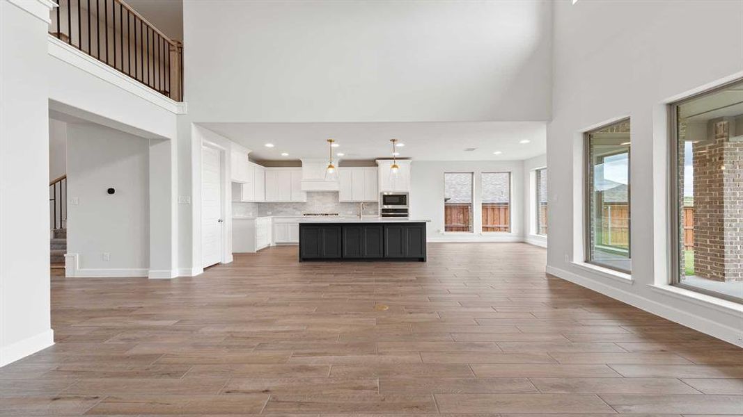 Unfurnished living room featuring a towering ceiling, light hardwood / wood-style floors, and sink