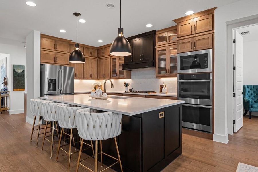A well-appointed kitchen features rich wood cabinetry, a generous island with seating, and integrated modern appliances. A well-appointed kitchen features rich wood cabinetry, a generous island with seating, and integrated modern appliances.