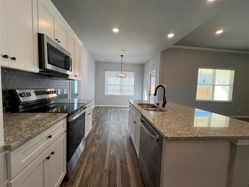 Kitchen featuring stainless steel appliances, dark wood-type flooring, sink, a center island with sink, and white cabinets