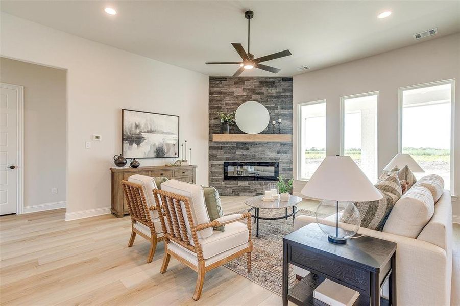 Living room featuring ceiling fan, a fireplace, and light hardwood / wood-style flooring