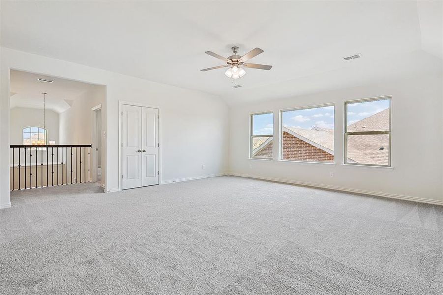 Carpeted empty room with ceiling fan and lofted ceiling