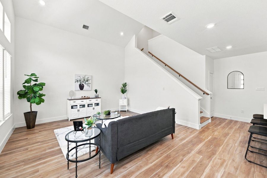 Open and airy living space showcasing the dramatic ceiling height, contemporary staircase, and seamless connection to the kitchen. Open and airy living space showcasing the dramatic ceiling height, contemporary staircase, and seamless connection to the kitchen.
