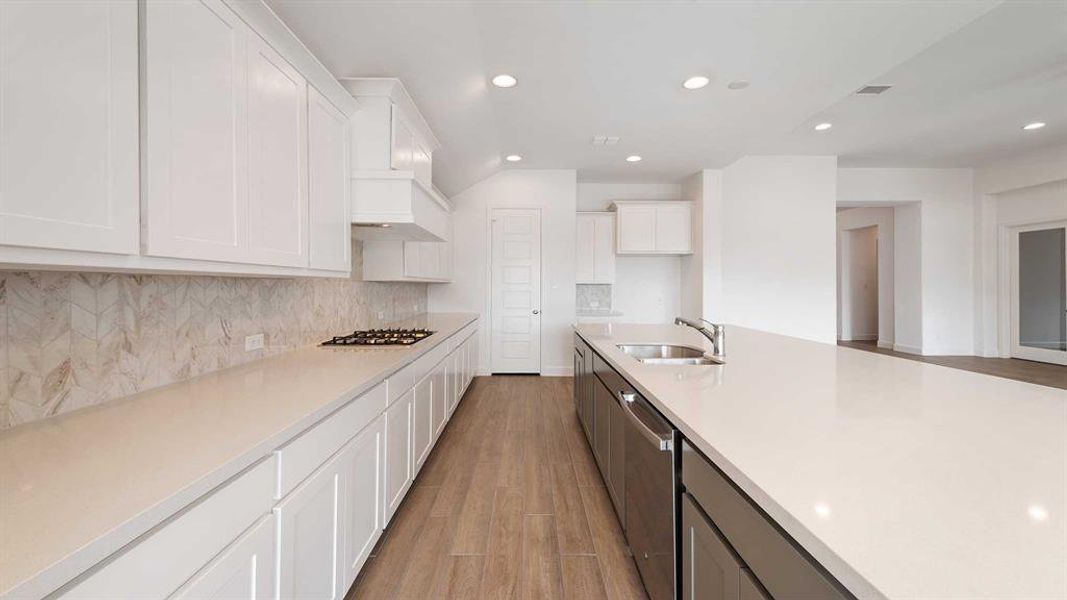 Kitchen with sink, white cabinets, light wood-type flooring, and stainless steel appliances