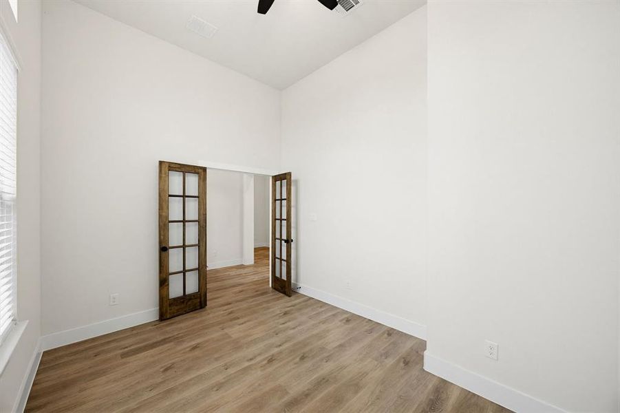 Bright interior room featuring wood-finish flooring, white walls, and a window with blinds