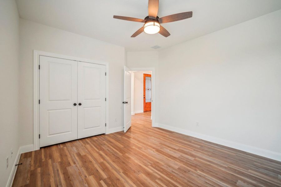Bedroom 3 featuring visible vents, a ceiling fan, a closet, light wood finished floors, and baseboards