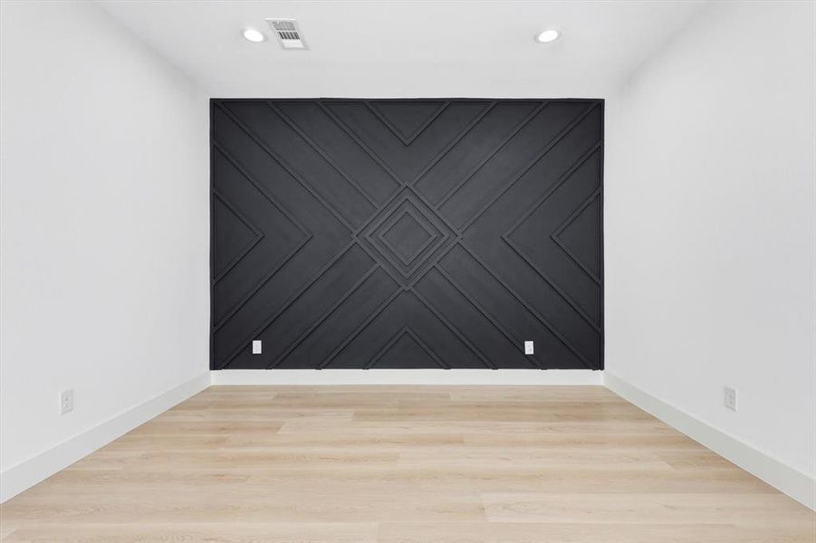 Accent wall with geometric wood paneling, wood-finish flooring, recessed lighting, white baseboards, and white painted walls Accent wall with geometric wood paneling, wood-finish flooring, recessed lighting, white baseboards, and white painted walls