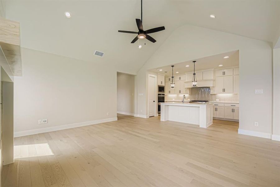 Unfurnished living room featuring light wood finished floors, high vaulted ceiling, recessed lighting, and ceiling fan