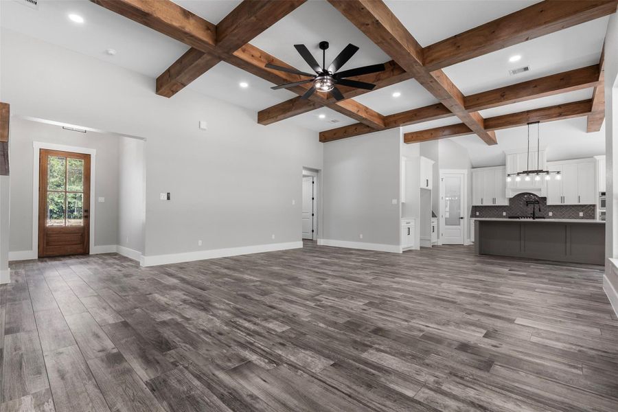 Open-concept living area flowing into a modern kitchen featuring a large island and stylish pendant lighting.