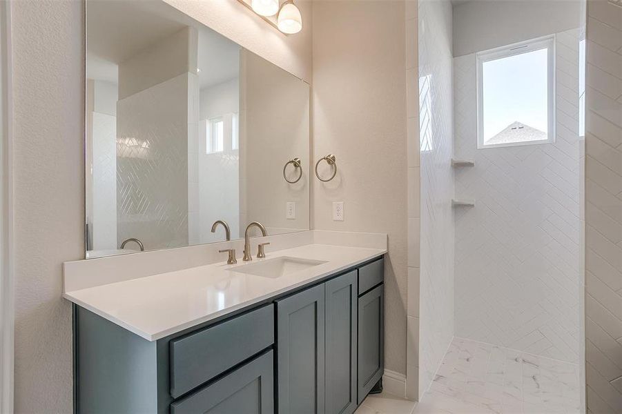 Bathroom featuring vanity and tiled shower