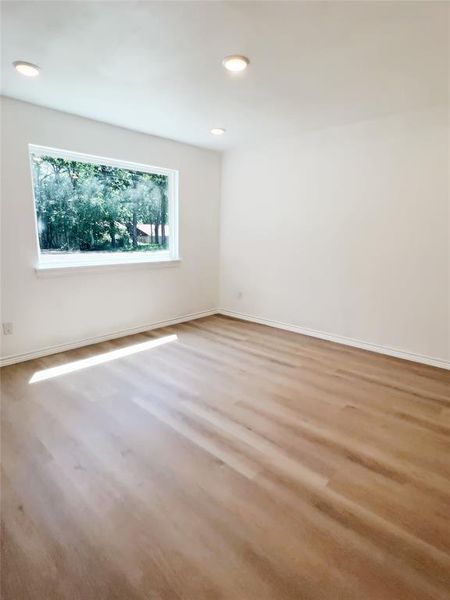 Bright room featuring a single window, recessed ceiling lighting, and wood-finish flooring