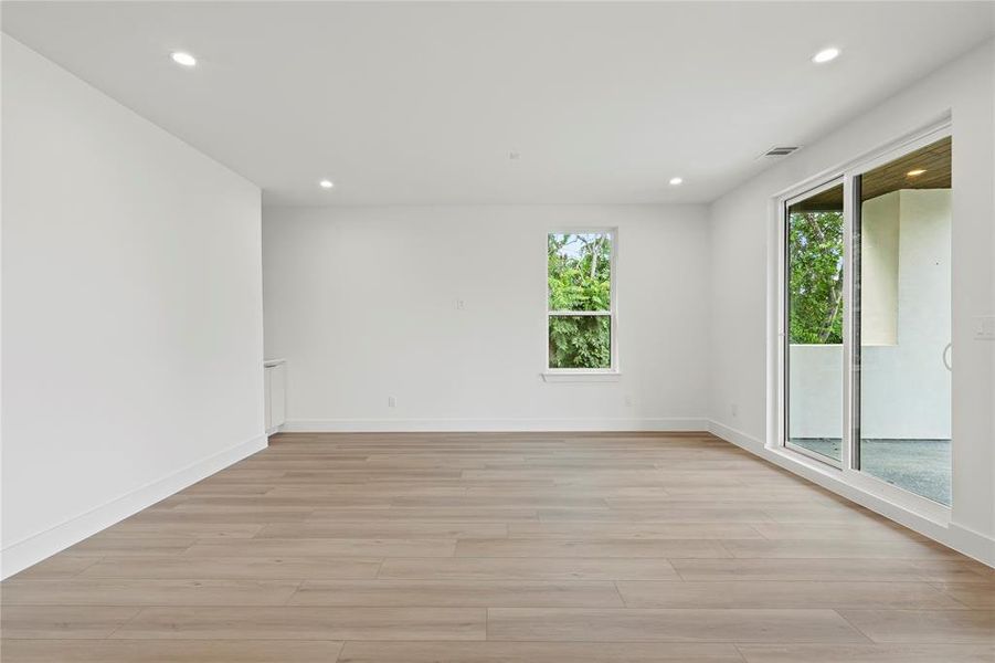 Unfurnished room with healthy amount of natural light, light wood finished floors, and recessed lighting