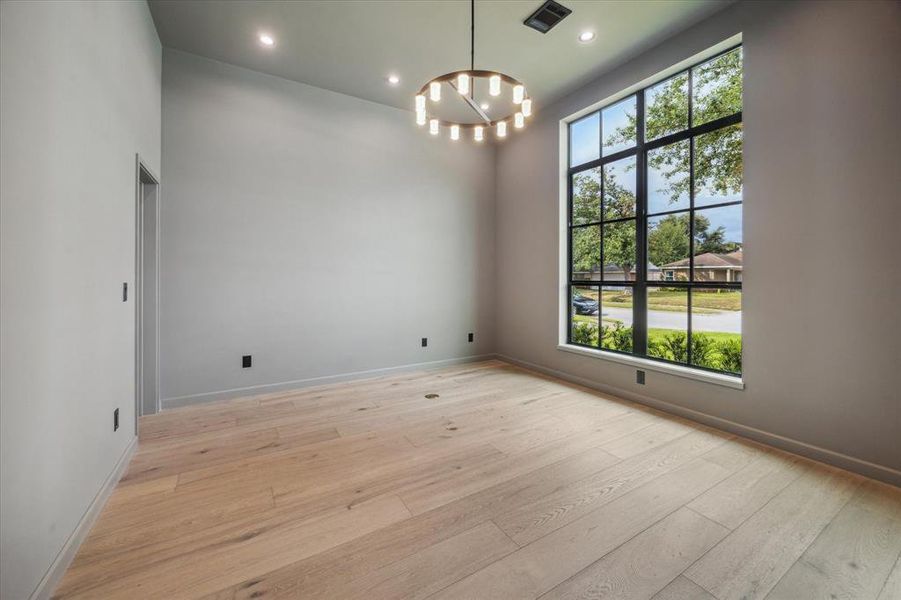 This private study, located at the front of the home, features floor-to-ceiling windows, recessed lighting, and plenty of space for productivity or relaxation.