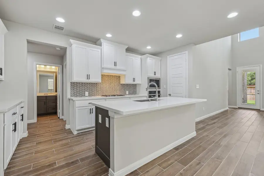 Kitchen with white gas cooktop, wood finished floors, a sink, light countertops, and recessed lighting Kitchen with white gas cooktop, wood finished floors, a sink, light countertops, and recessed lighting