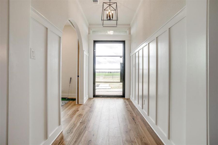 Doorway featuring wood finished floors, a chandelier, and arched walkways