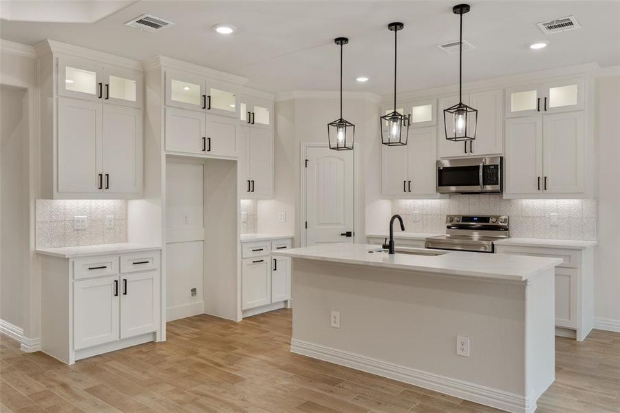 Kitchen featuring appliances with stainless steel finishes, decorative backsplash, a center island with sink, and sink