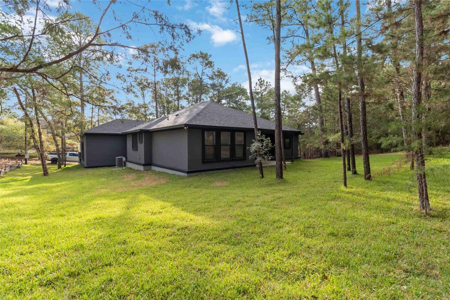 View of side of property featuring roof with shingles, a lawn, and stucco siding