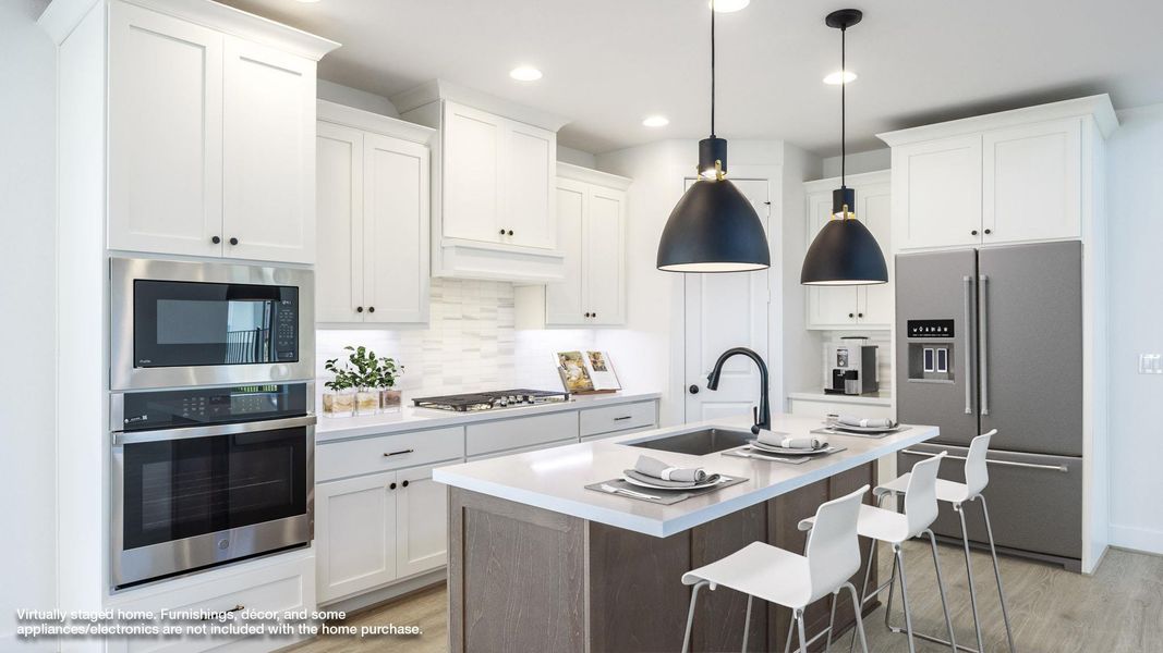 Kitchen featuring appliances with stainless steel finishes, backsplash, a breakfast bar, a kitchen island with sink, and light wood finished floors Kitchen featuring appliances with stainless steel finishes, backsplash, a breakfast bar, a kitchen island with sink, and light wood finished floors