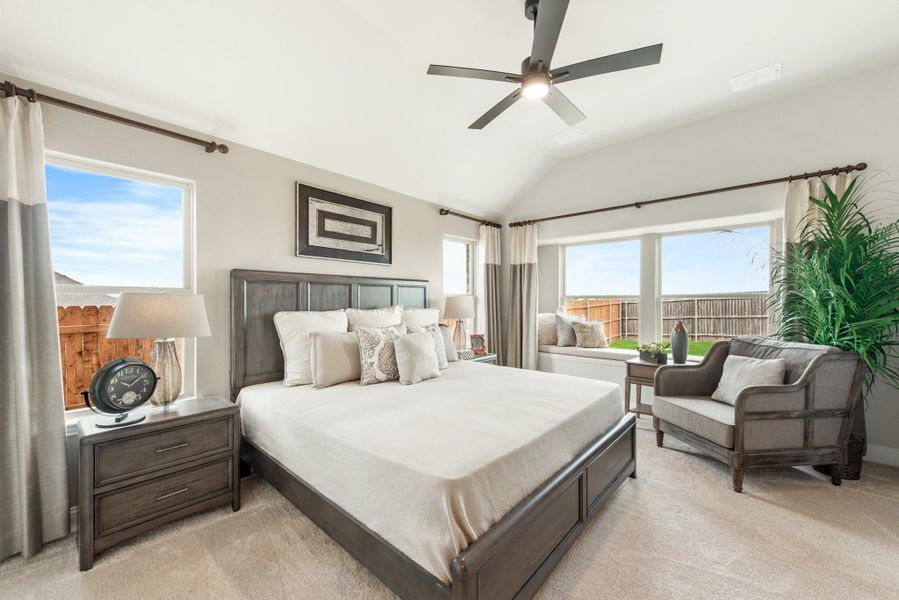 Master bedroom with vaulted ceiling, ceiling fan, king bed, and large windows with natural light