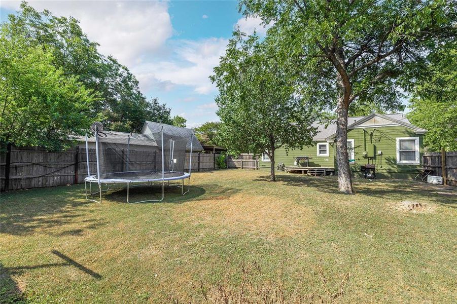 Fenced backyard with a trampoline and a deck Fenced backyard with a trampoline and a deck