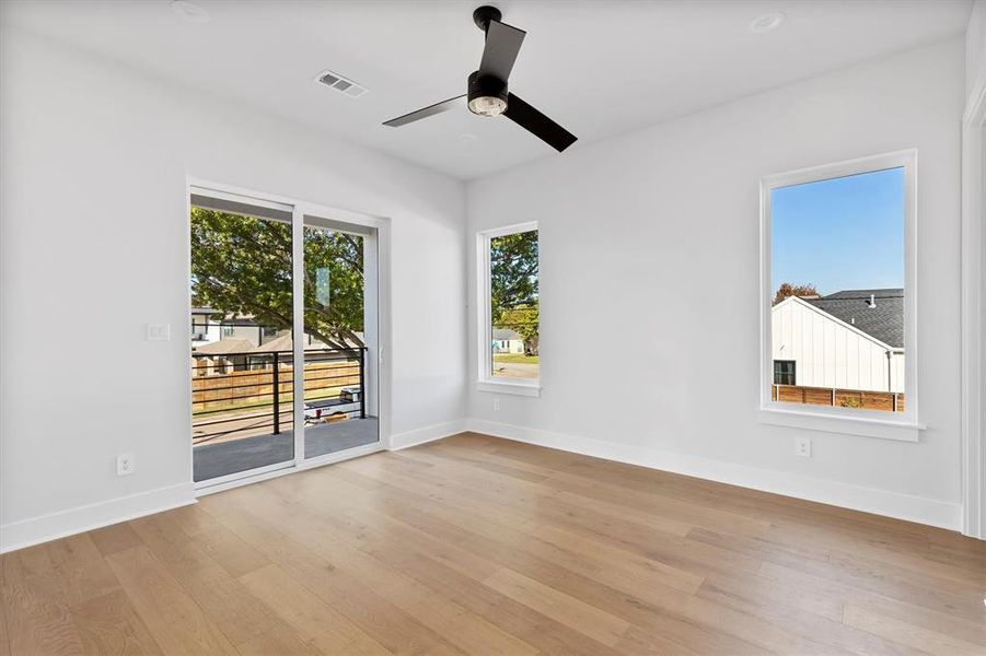 Empty room featuring ceiling fan, plenty of natural light, and light hardwood / wood-style floors