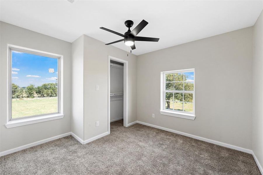 Unfurnished bedroom featuring light colored carpet and a ceiling fan Unfurnished bedroom featuring light colored carpet and a ceiling fan