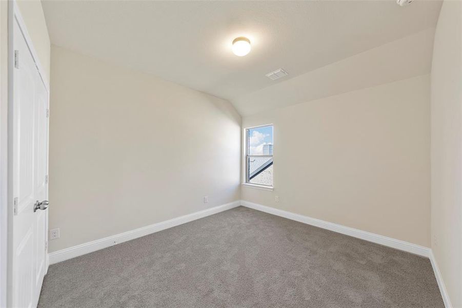 Spare room with carpet floors and vaulted ceiling