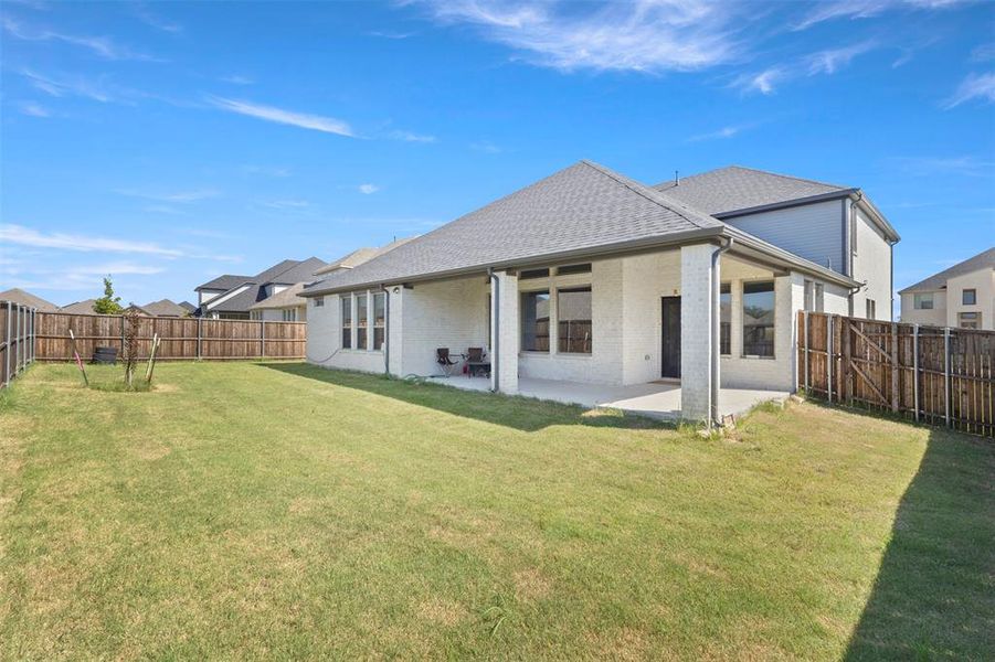 Rear view of house featuring a fenced backyard, a patio area, brick siding, and a shingled roof