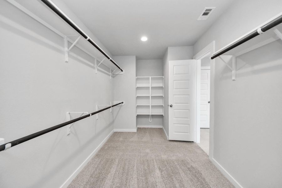 Walk-in closet that epitomizes luxury and practicality. This generously sized space features built-in shelving, offering abundant room for impeccable organization. High ceilings and recessed lighting create a bright and welcoming ambiance. Sample photo of completed home with similar floor plan. Actual colors and selections may vary. Walk-in closet that epitomizes luxury and practicality. This generously sized space features built-in shelving, offering abundant room for impeccable organization. High ceilings and recessed lighting create a bright and welcoming ambiance. Sample photo of completed home with similar floor plan. Actual colors and selections may vary.