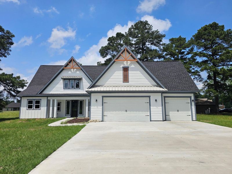 Modern farmhouse with a three-car garage, a charming gabled roof, and a large driveway.